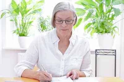 © agenturfotografin - stock.adobe.com Ältere Dame bearbeitet Unterlagen